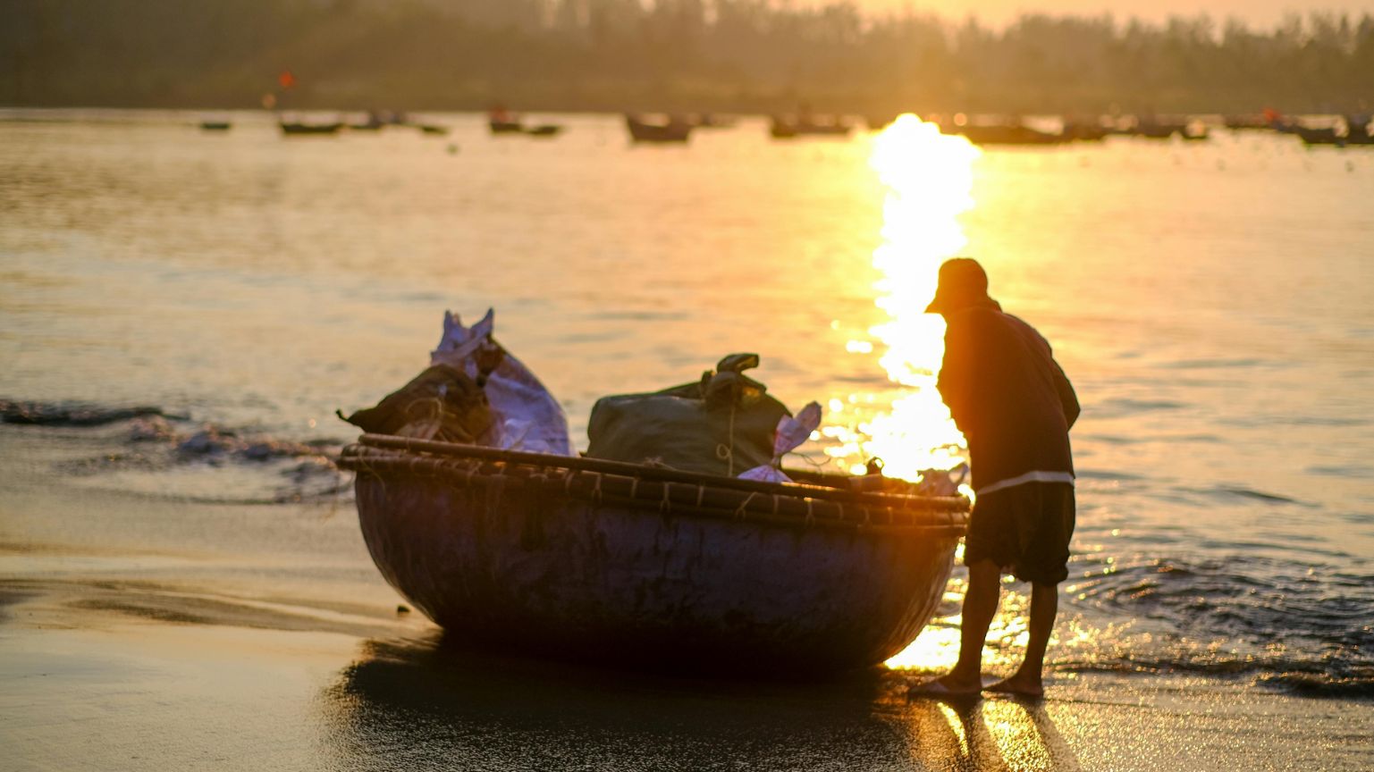 Fisherman with basket boat at sunrise on My Khe Beach, Da Nang.
