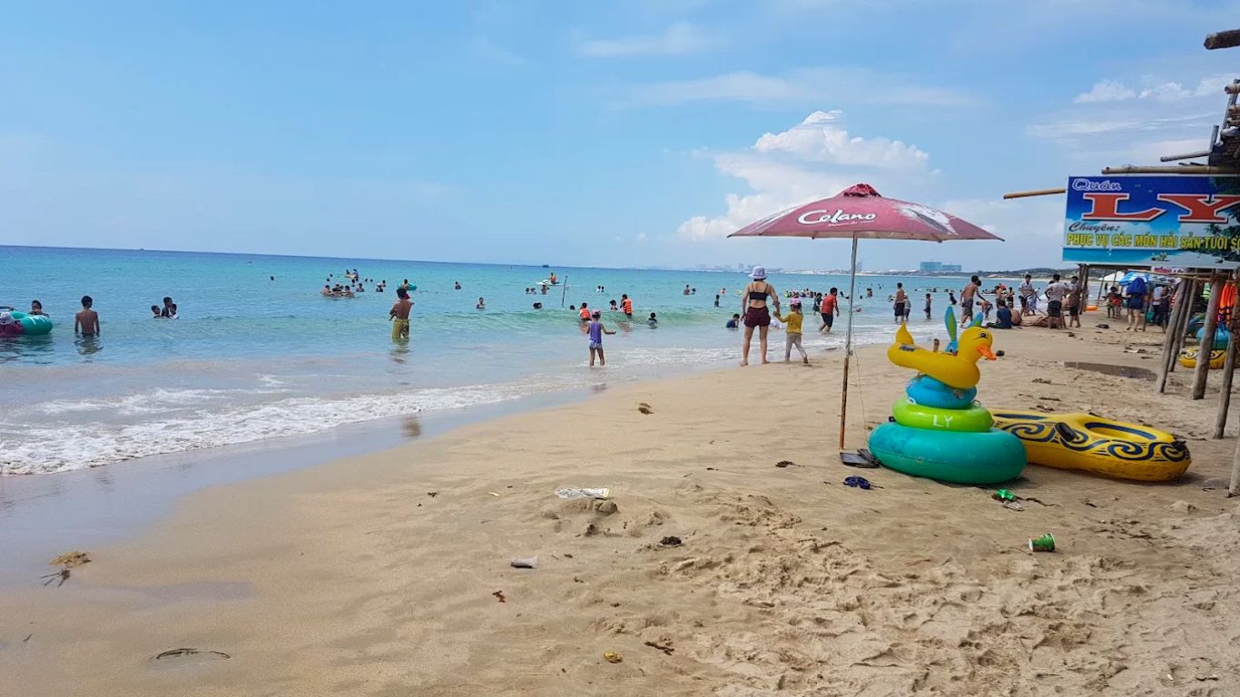 Nha Trang beach in July peak season with families swimming and crowded shoreline during summer holidays