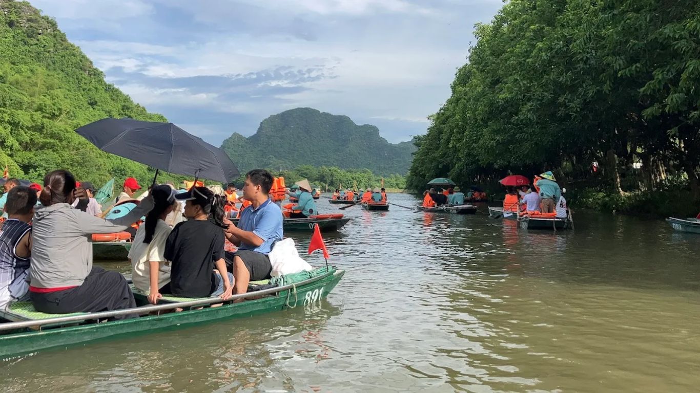 Crowded boat tours at Ninh Binh during Vietnam domestic summer holiday season in July
