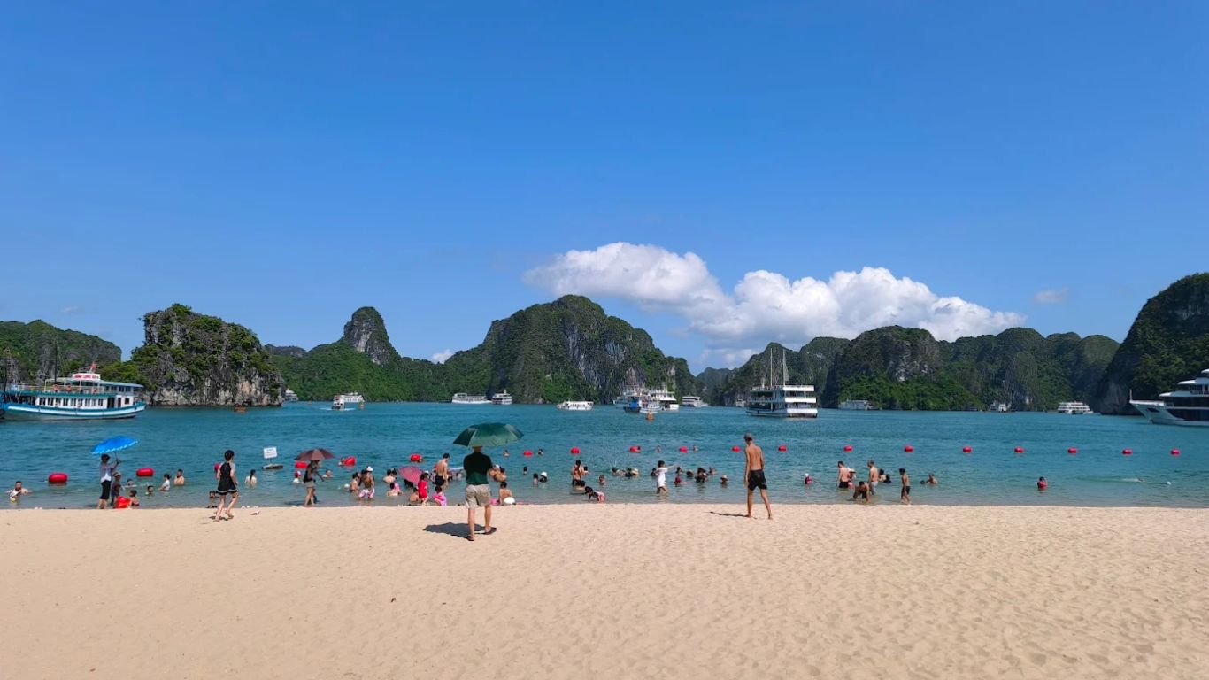 Halong Bay in July busy beach summer vacation families swimming karst backdrop