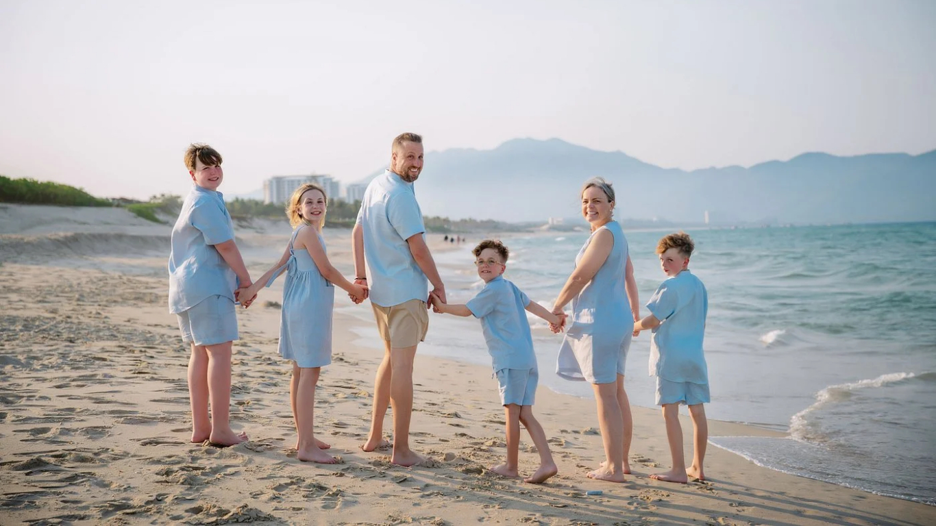 Family holding hands on An Bang Beach near Hoi An at sunset